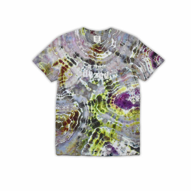 An artisanal ice-dyed t-shirt, its surface a canvas of swirling blues, purples, and chartreuse resembling geode formations, with the text 'dazed' in a stylized, icy lettering at the center.