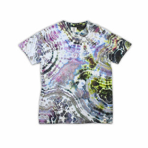 An artisanal ice-dyed t-shirt, its surface a canvas of swirling blues, purples, and chartreuse resembling geode formations, with the text 'dazed' in a stylized, icy lettering at the center.