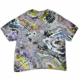 An artisanal ice-dyed t-shirt, its surface a canvas of swirling blues, purples, and chartreuse resembling geode formations, with the text 'dazed' in a stylized, icy lettering at the center.