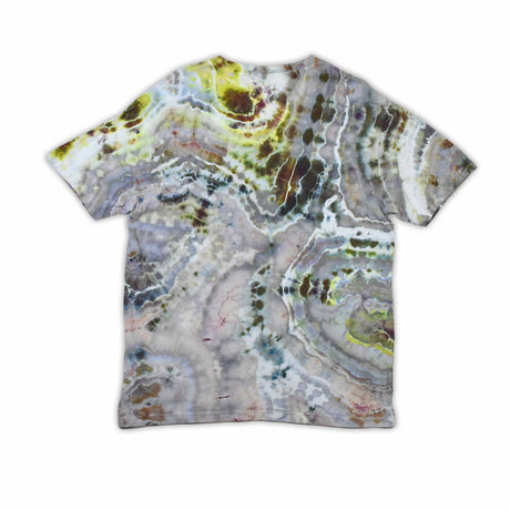 An artisanal ice-dyed t-shirt, its surface a canvas of swirling blues, purples, and chartreuse resembling geode formations, with the text 'dazed' in a stylized, icy lettering at the center.