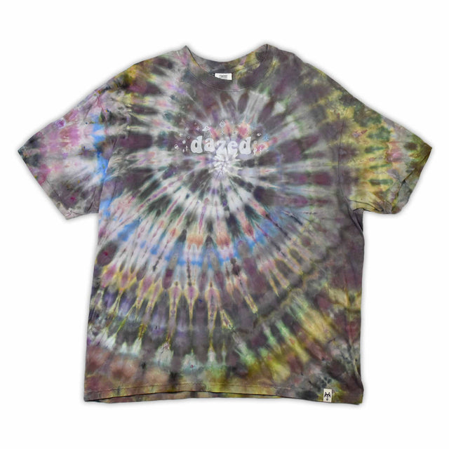 This t-shirt displays an intricate ice-dye effect that creates a starburst pattern with a mix of earthy and vibrant colors, highlighted by 'dazed' text in the middle in a style reminiscent of melting ice.