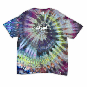 This t-shirt displays a stunning ice-dye technique creating a crystalline effect with vibrant blues, purples, and greens emanating outwards, with 'dazed' situated in the middle in a funky font.