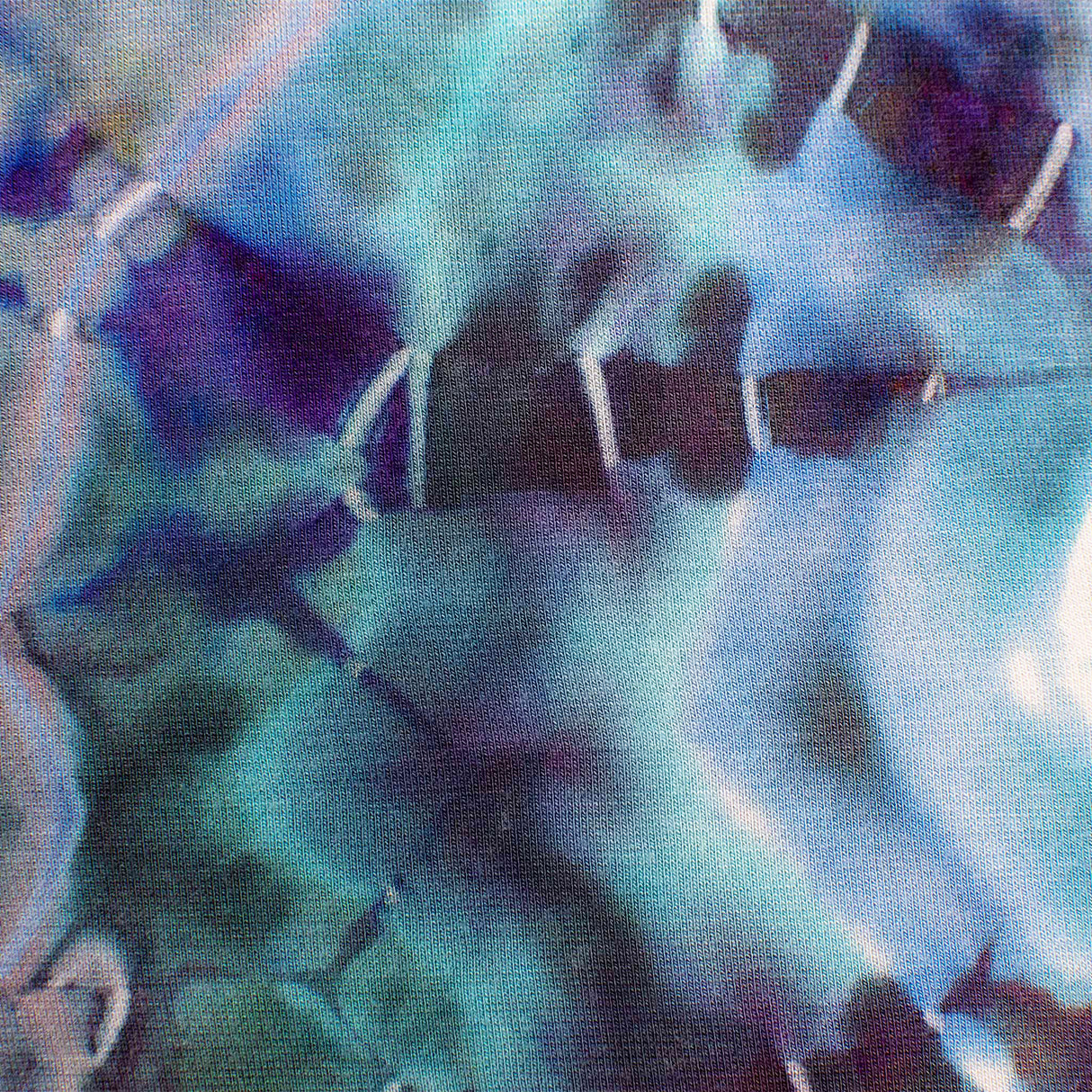 A pair of hand-dyed pants showcasing a unique ice-dye technique with organic patterns in a striking combination of sapphire, violet, and seafoam green.