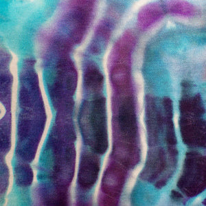 A pair of hand-dyed pants showcasing a unique ice-dye technique with organic patterns in a striking combination of sapphire, violet, and seafoam green.