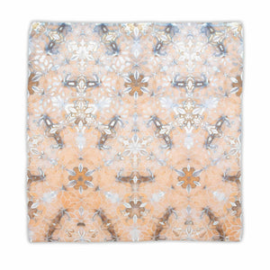 Earth-toned tie-dyed bandana displaying a symmetrical pattern with elements that suggest flowers and stars, in a soft palette of beige, grey, and white.