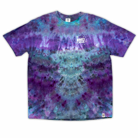 The 'Dinkey Creek' logo pops against the swirling backdrop of an ice dye design in rich purples and blues on this comfortable t-shirt.