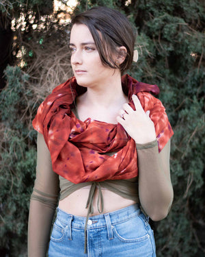 A richly colored shawl with an intricate pattern of deep red and orange hues is elegantly draped over the shoulders, catching the light and adding a luxurious layer to the attire.