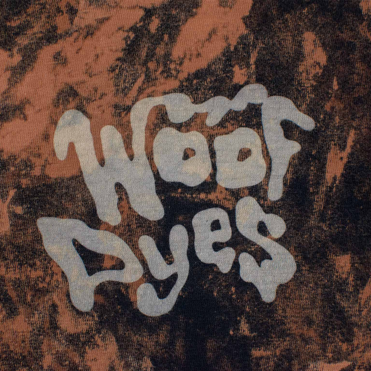 A stylish bleached t-shirt makes a statement with the 'Woof Dyes' logo, amidst a mottled backdrop of blacks and browns for a rugged look.