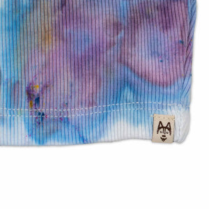 A women's high-neck cropped tank top featuring a soft ice dye pattern with swirls of blue, purple, and white on a white background, creating a dreamy, cloud-like effect. 